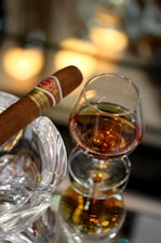 Elegant setting with a glass of fine wine, a cigar, and the orange cardholder resting on a polished wooden table.