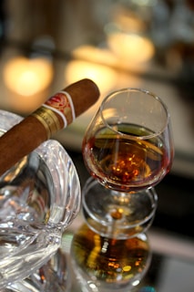 A sophisticated lounge setting with a glass of whiskey and a Bawono Cigar on a polished wooden surface.