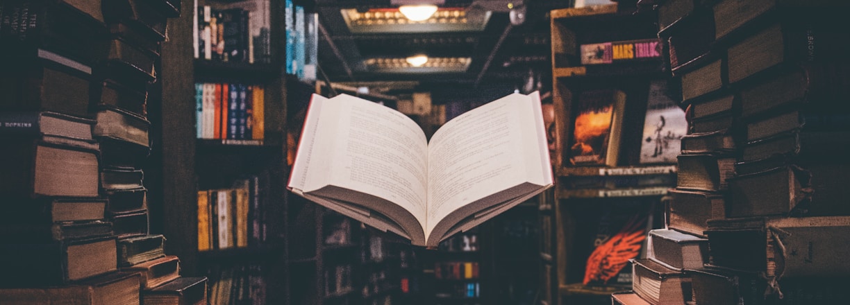 view of floating open book from stacked books in library