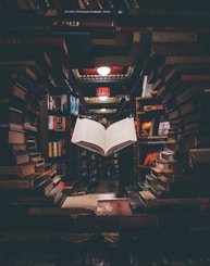 view of floating open book from stacked books in library