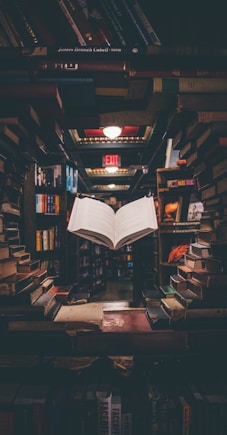 view of floating open book from stacked books in library