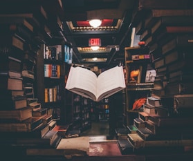 view of floating open book from stacked books in library