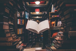 view of floating open book from stacked books in library