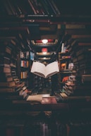 view of floating open book from stacked books in library