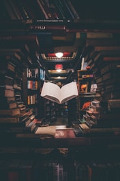 view of floating open book from stacked books in library