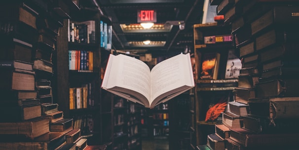 view of floating open book from stacked books in library