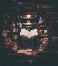 view of floating open book from stacked books in library