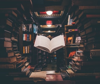 view of floating open book from stacked books in library