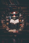 view of floating open book from stacked books in library