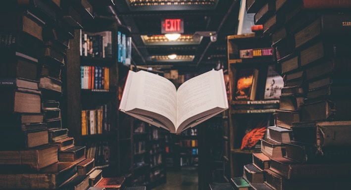 view of floating open book from stacked books in library