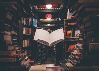 view of floating open book from stacked books in library