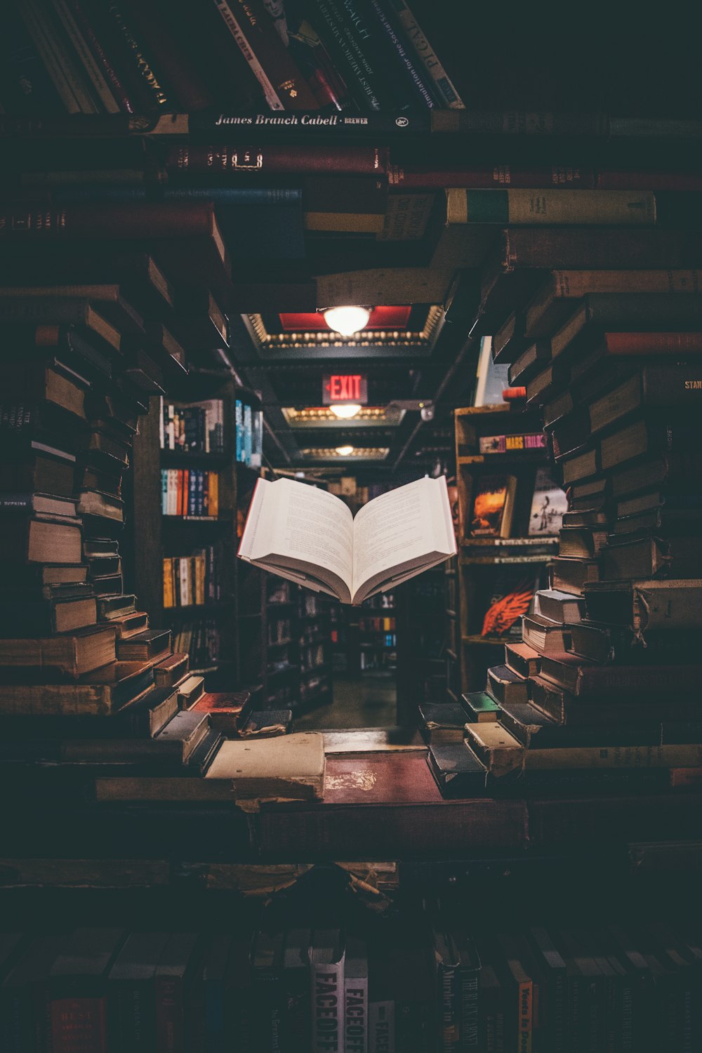 Ansicht eines schwebenden geöffneten Buches aus gestapelten Büchern in der Bibliothek