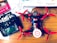 A drone with red propellers is placed on a wooden surface next to a remote control labeled 'FLYSKY'. Various documents and a book on mechanical engineering are scattered around. The drone appears to be in the process of assembly, with visible wiring and components.
