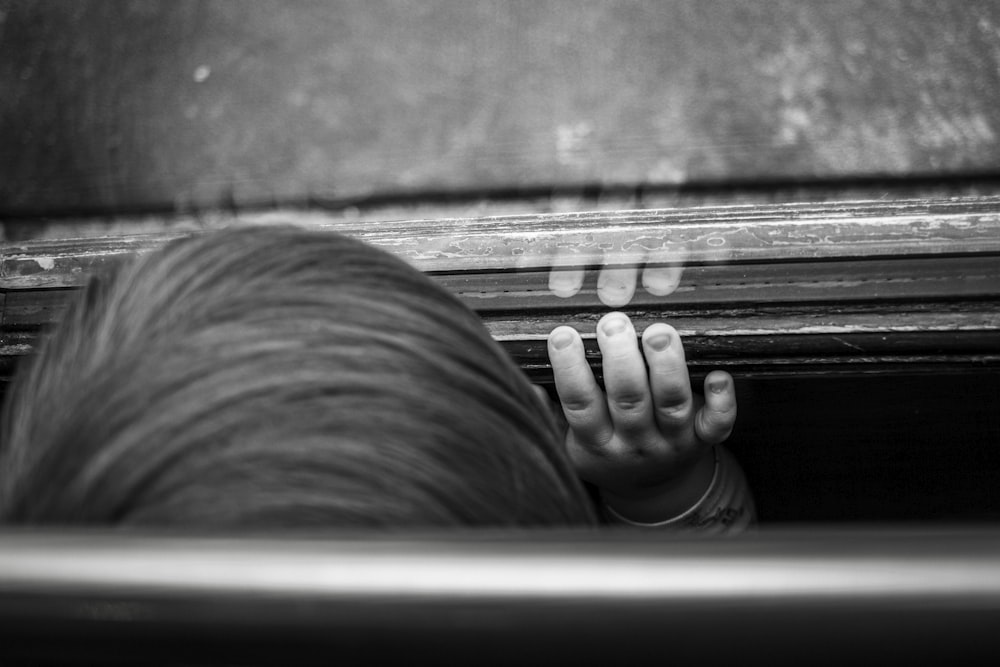 grayscale photography of boy standing in front of glass mirror