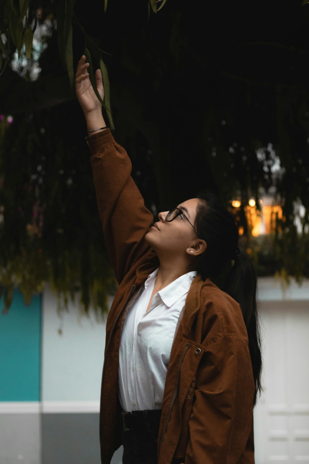 a woman reaching up into the air to catch a leaf