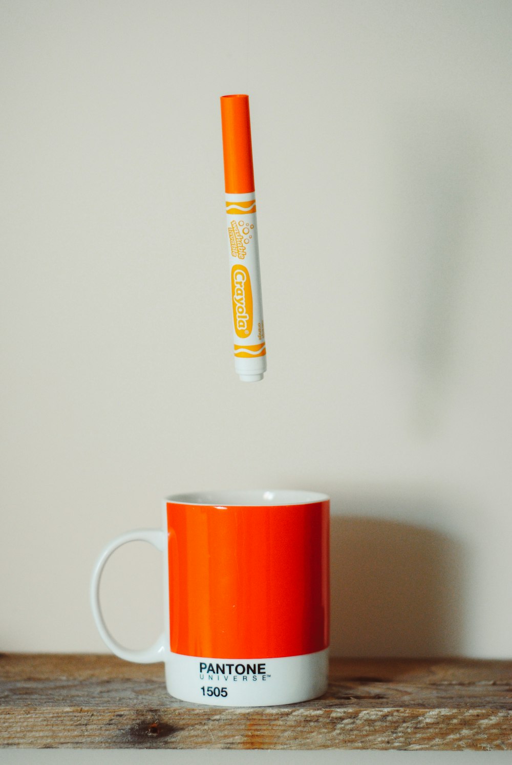 orange Crayola crayon pen above mug
