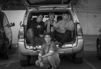 Four friends standing beside a tow truck, smiling and ready to help.