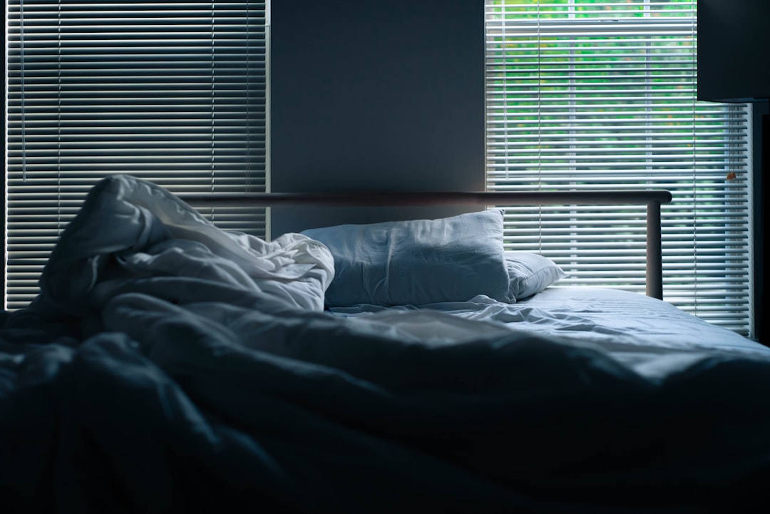  gray bedding beside window blinds sheet