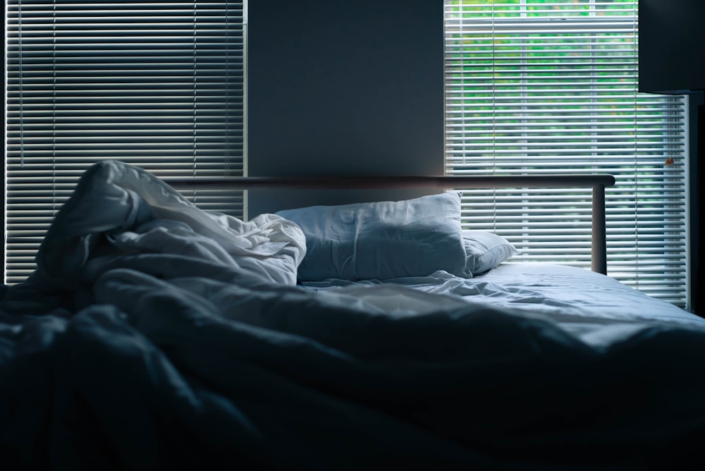 gray bedding beside window blinds