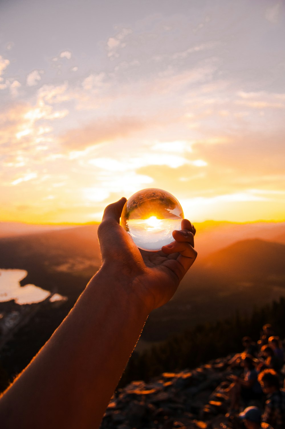 person holding glass ball reflecting sun