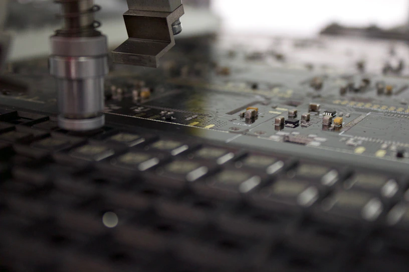 Close-up of a sleek robotic arm assembling a complex circuit board under bright lab lights.