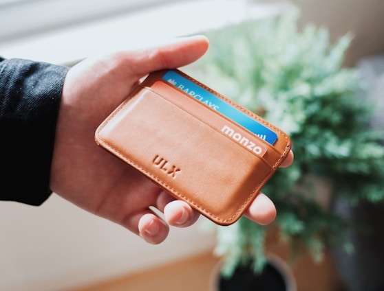 person holding brown ULX leather wallet