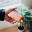person holding brown ULX leather wallet