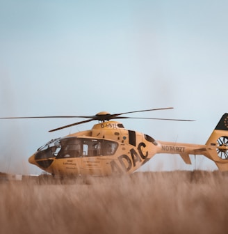 brown helicopter landing on brown grass field during daytime