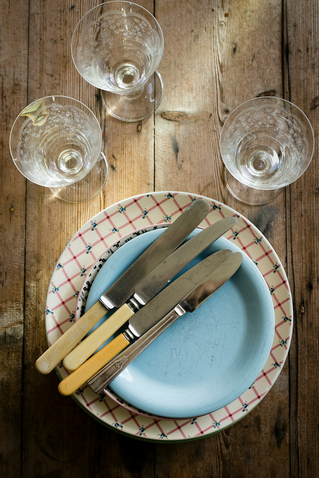 flat-lay photography of stem glasses, saucers, plate, and bread and butter knives