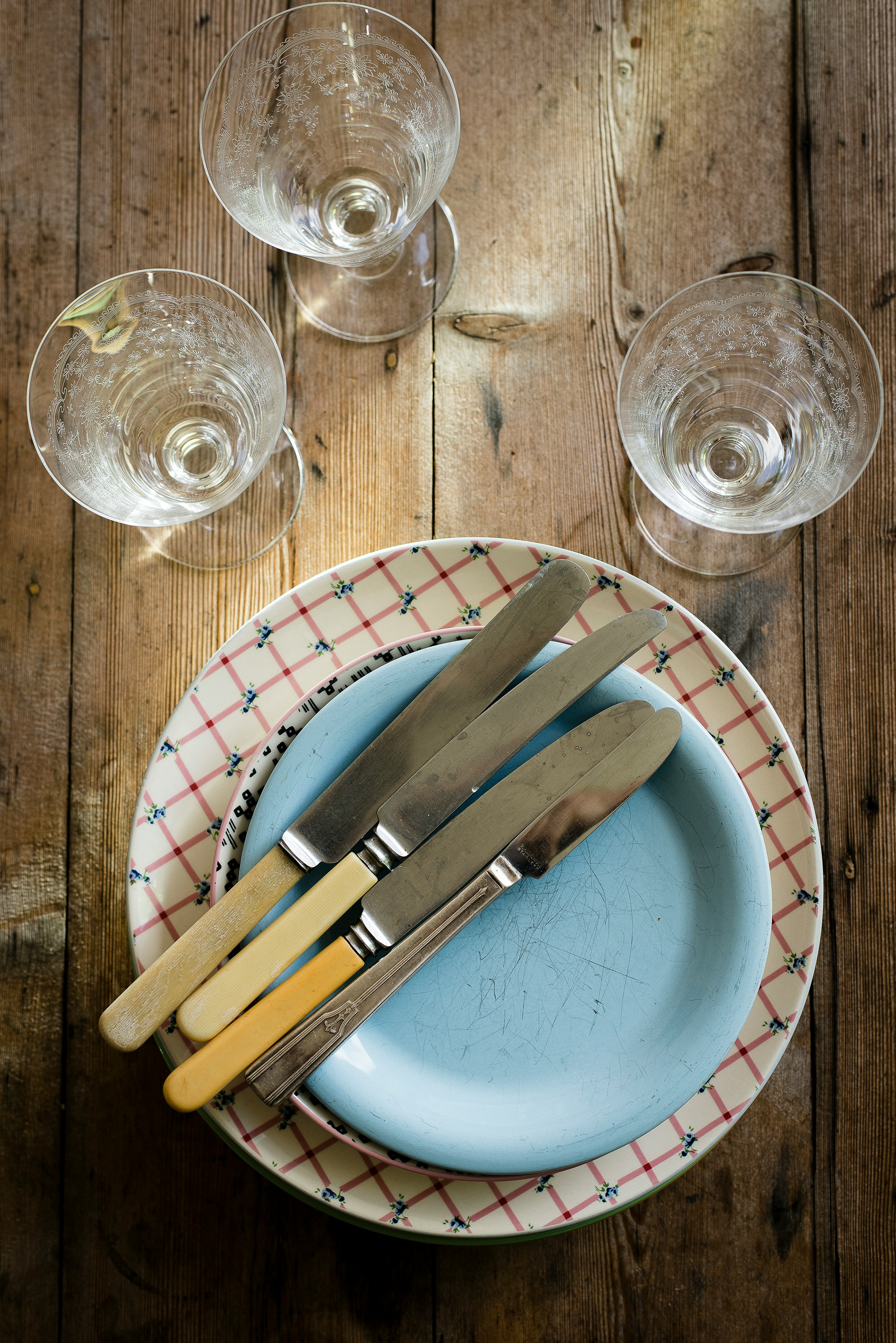 flat-lay photography of stem glasses, saucers, plate, and bread and butter knives