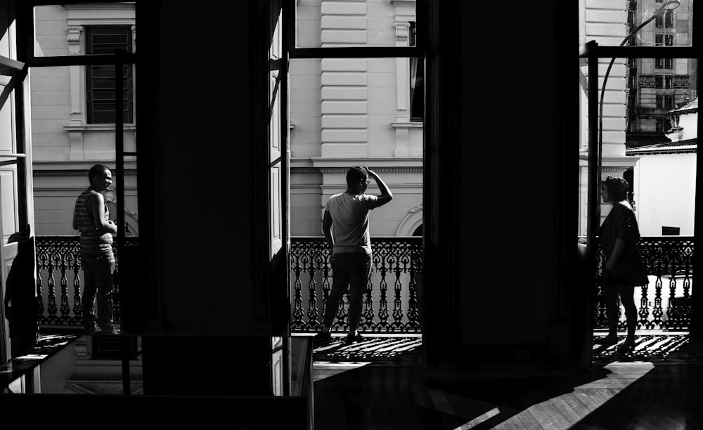 grayscale photo of three people on terrace