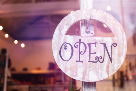 Close-up of a business owner proudly displaying their shop sign in a small town.