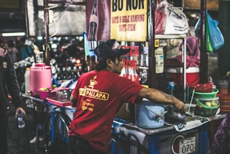 Coffee vendor preparing drinks in a busy market environment.