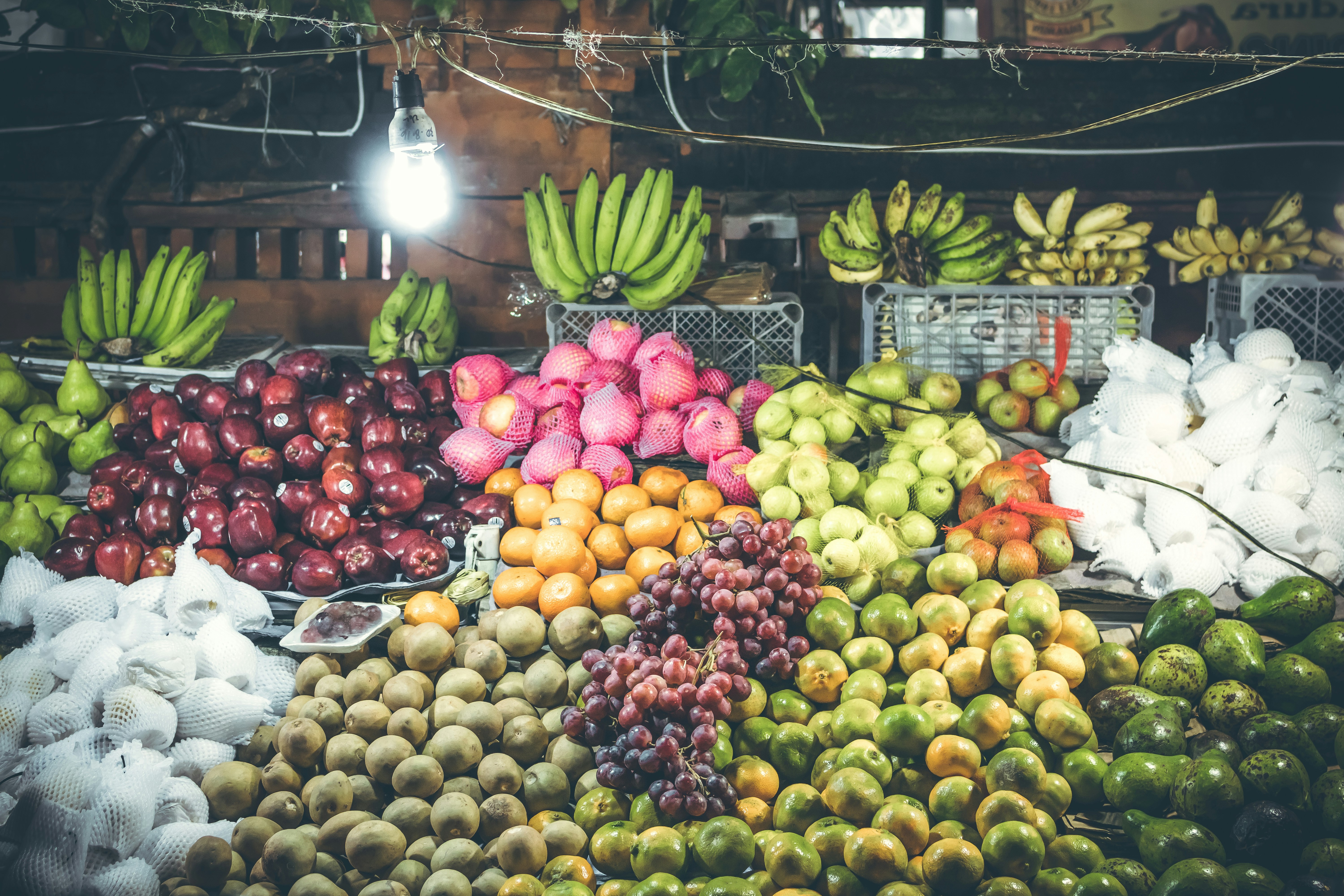 Colorful fresh fruits displayed in a market with vibrant lighting