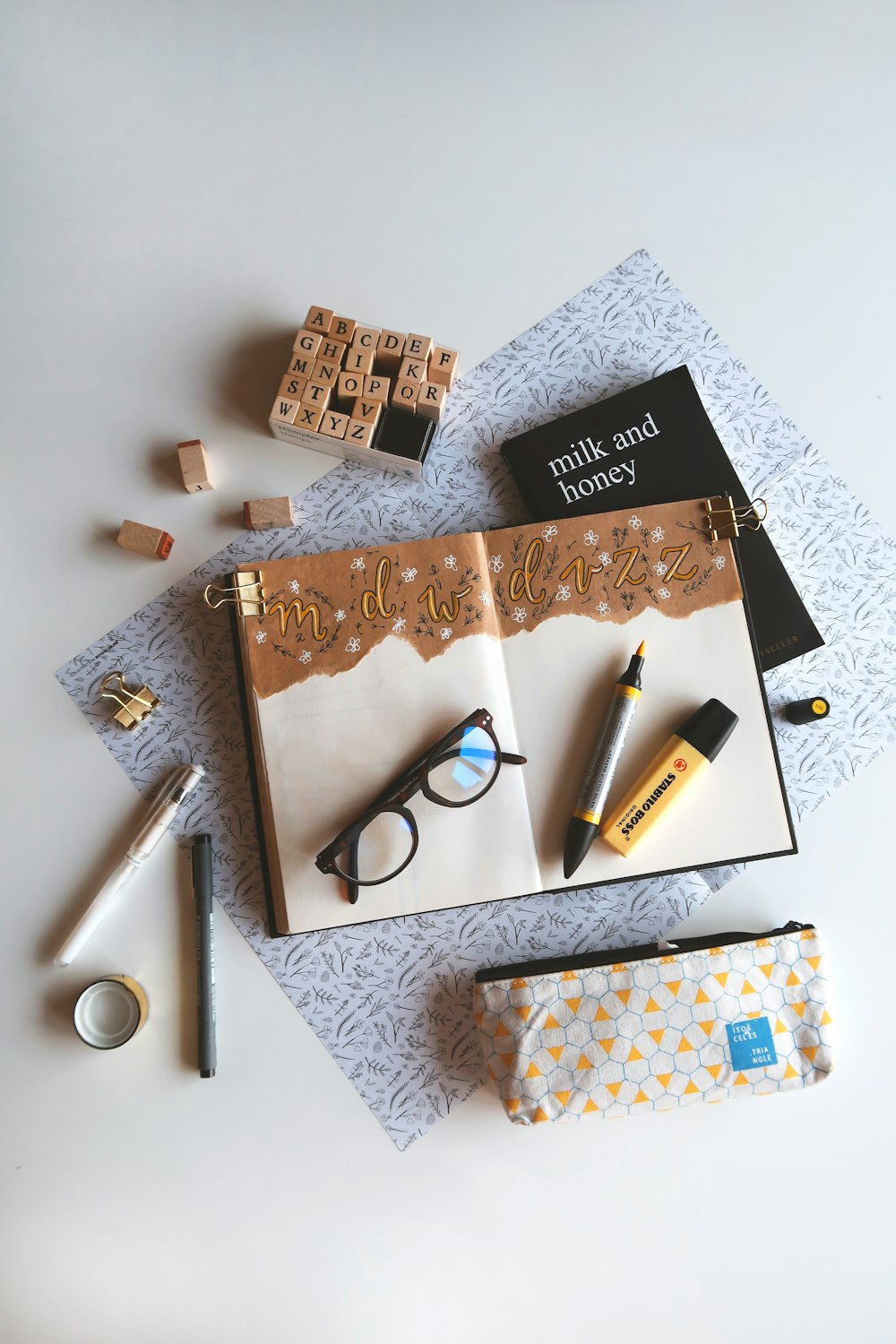 book, marker pen, and eyeglasses on white surface