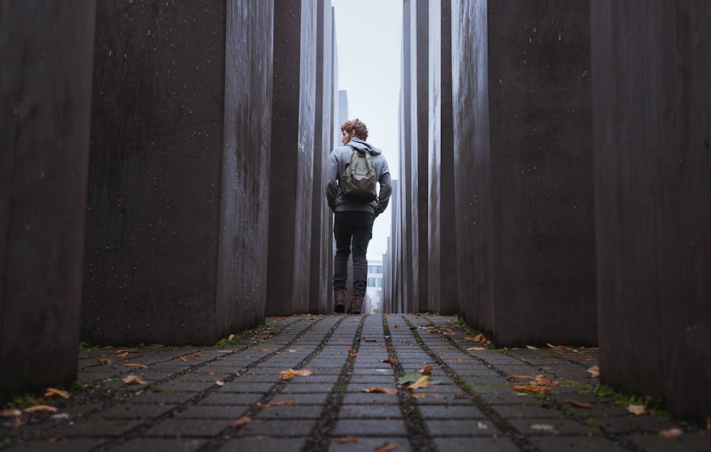 man walking through gray walls