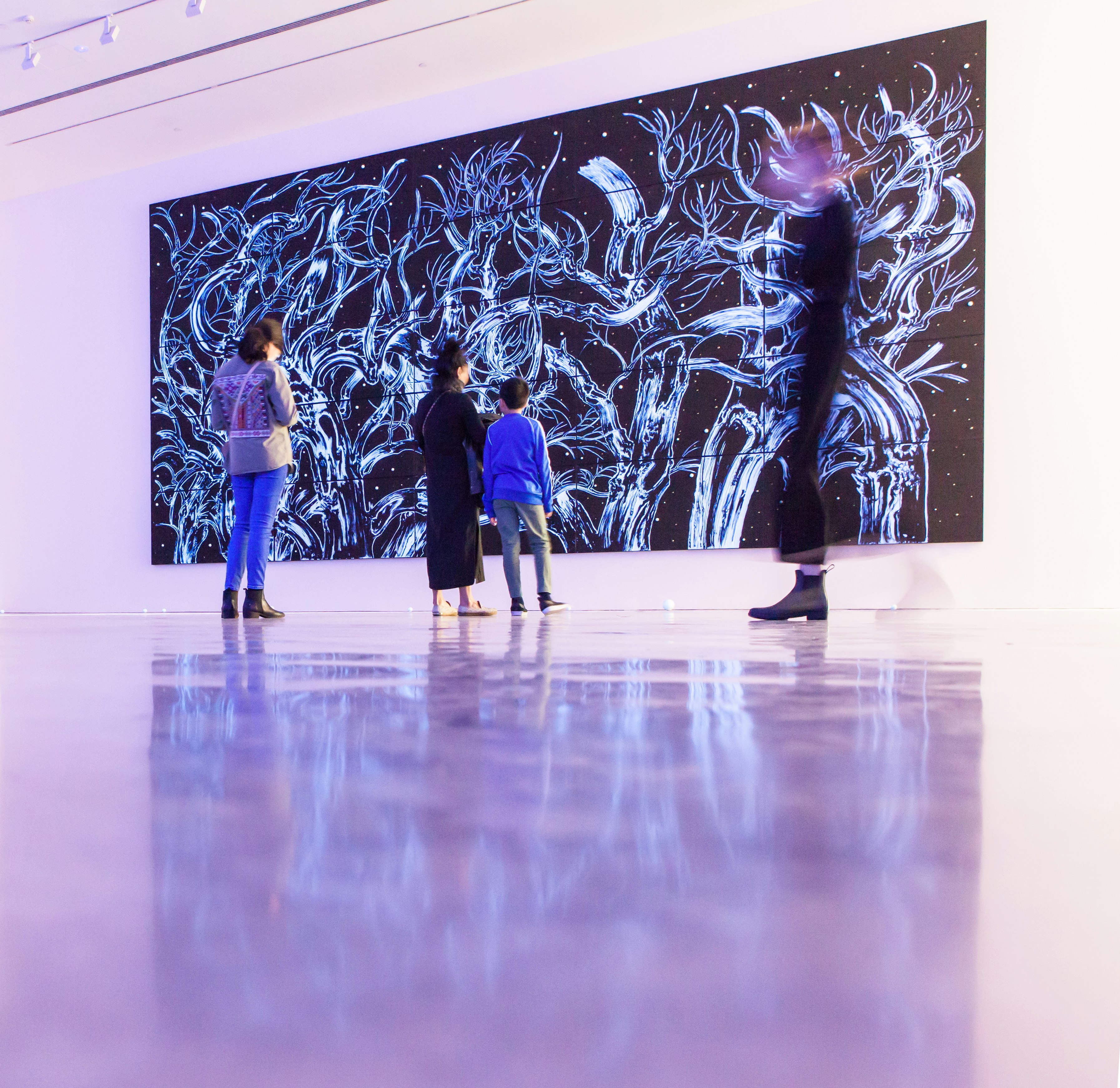 four people standing in front of abstract painting