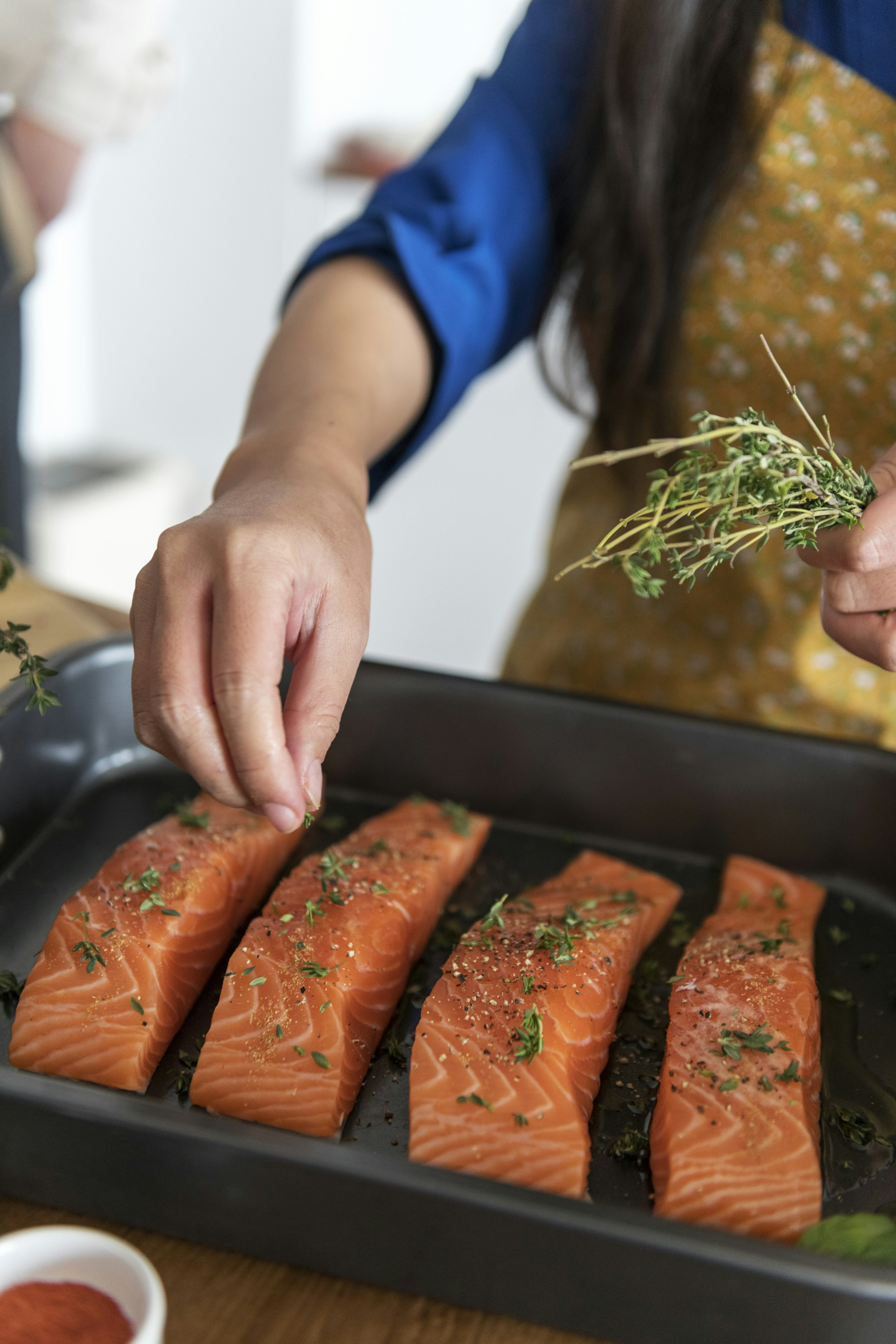 person garnishing fish with green herbs
