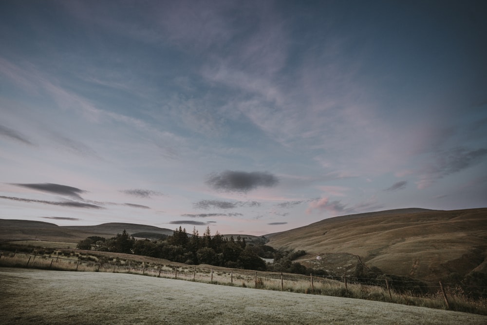 open field with hill in distance at daytime