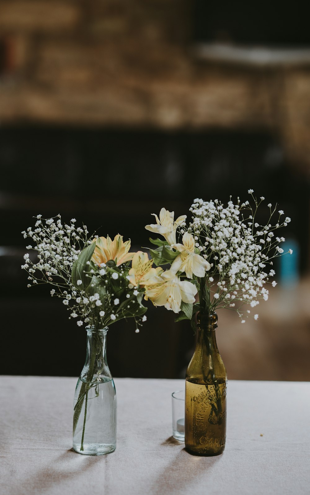 flores brancas e amarelas em garrafas de vidro transparente