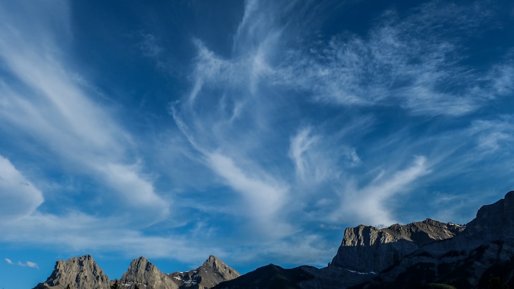 rock mountains under cirrus clouds