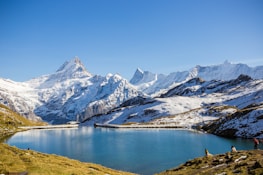 A serene mountain landscape with hikers enjoying the panoramic views under a clear blue sky.