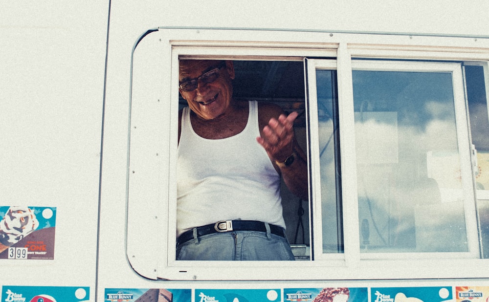 man wearing white tank top near window