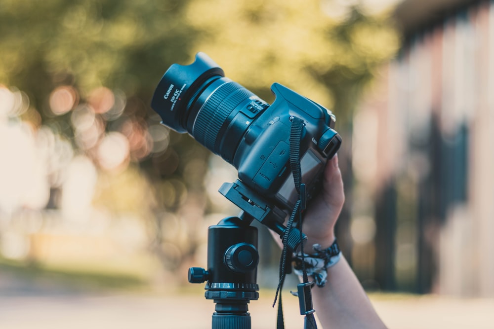 fotografia con messa a fuoco selettiva di una persona che tiene in mano una fotocamera DSLR