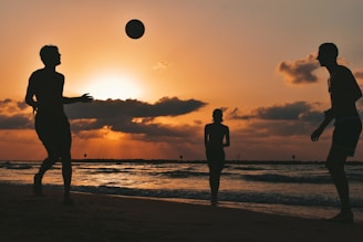 silhouette of man and woman standing on beach during sunset