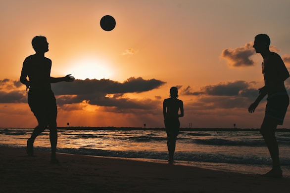 silhouette of man and woman standing on beach during sunset