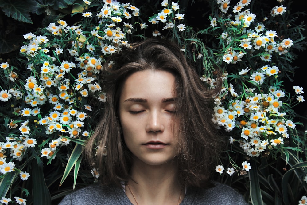 mujer cerrando los ojos en flor blanca