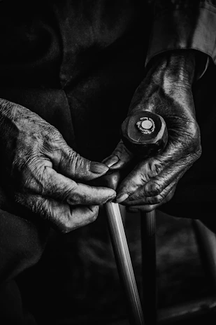 A blind Black woman using a white cane, gently guided by a caring family member, with a warm red, white, and black color palette.