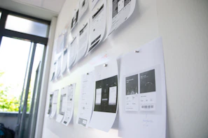 A designer reviewing printed samples of various print formats on a bright desk.
