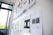 A series of printed pages with design layouts are pinned to a whiteboard in a brightly lit room. The pages appear to be drafts or wireframes of web or app designs, featuring various text and graphical elements. Sunlight filters through nearby windows, creating a mix of natural and artificial lighting.